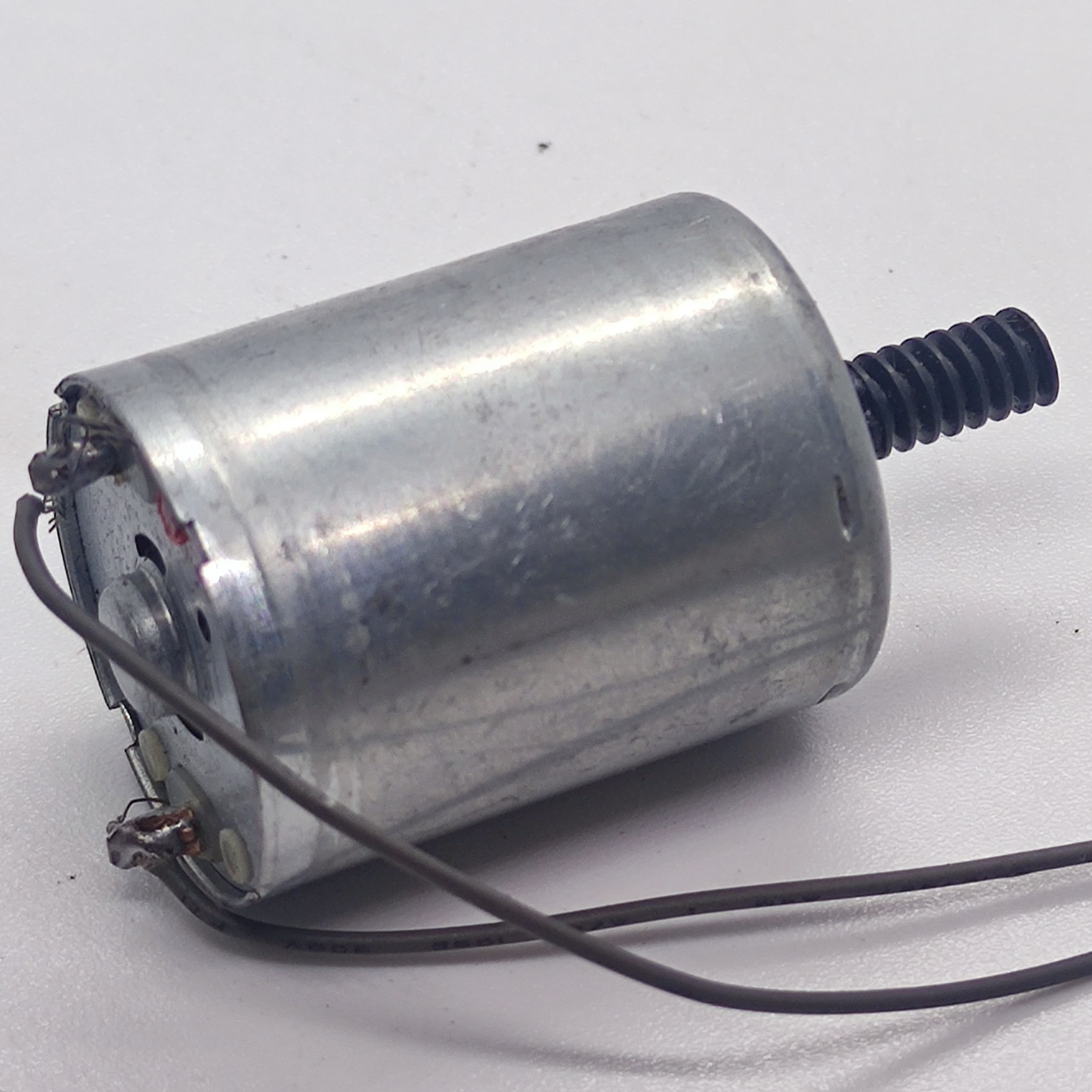 DC Motor 2V To 24V 5100RPM - a silver cylindrical motor with a black worm gear on the shaft and two brown wires soldered to the rear terminals.
