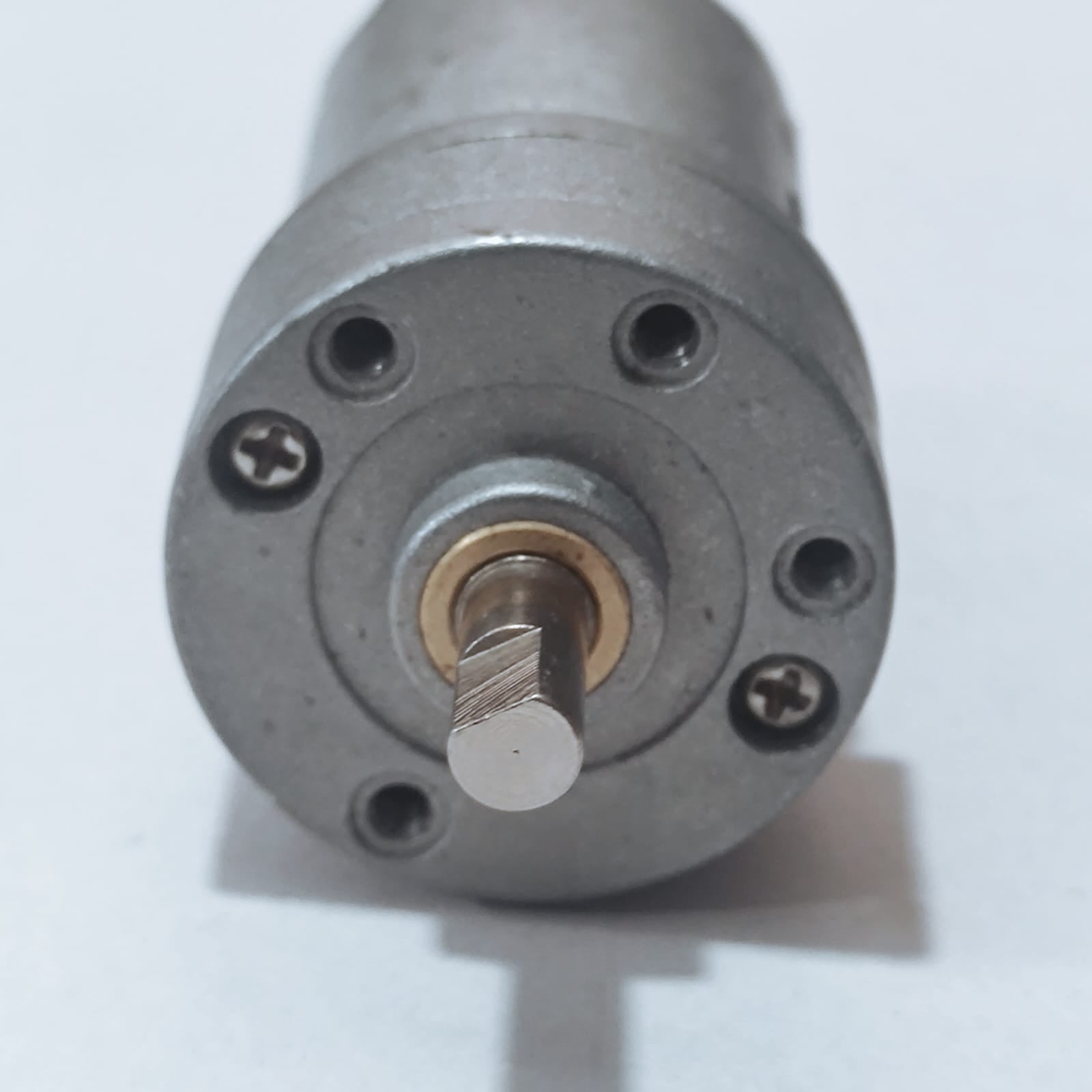 DC Motor DC Electric Geared Motor - a close-up shot of the silver metallic front face showing the circular mounting holes and the D-shaped output shaft.