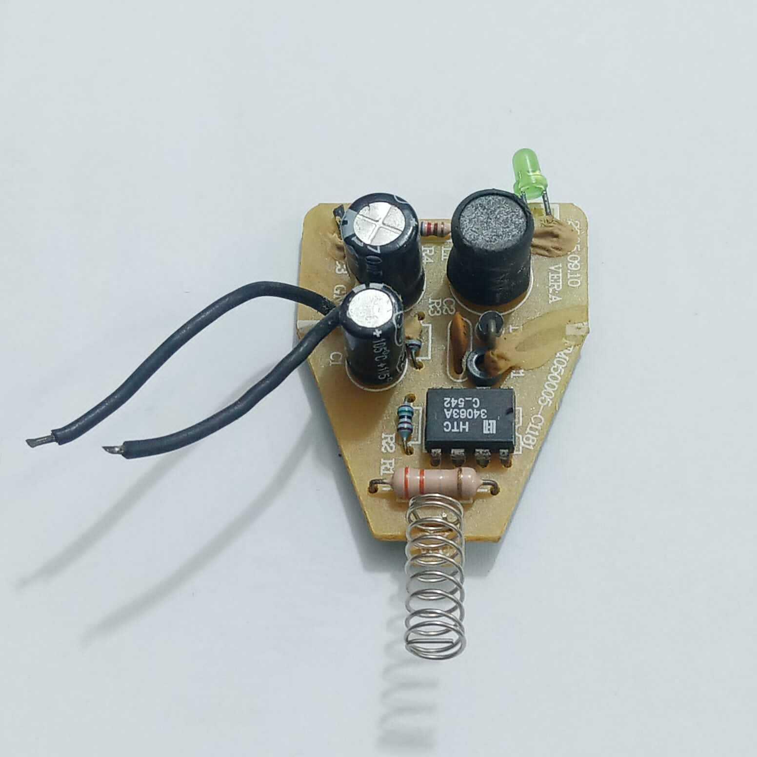 DC To DC Convertor IC 34063A - a black chip, two cylindrical capacitors, a spring contact, a green LED, and two black input wires.