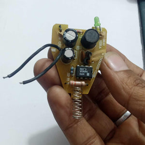 DC To DC Convertor IC 34063A - a yellow circuit board held in a hand with a green LED, a black buzzer, two capacitors, and a metal spring.