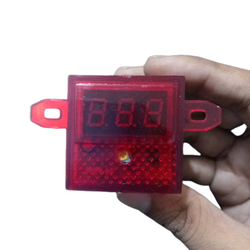 DC Volt Meter 8-30V - held in a hand, featuring a red rectangular housing with a three-digit LED display and a small circular indicator light.