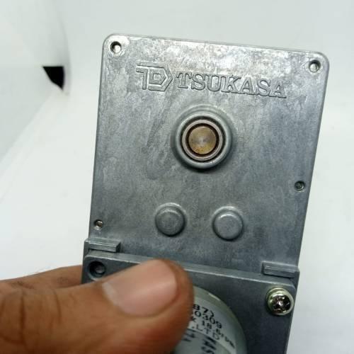 DC Worm Gear Motor AXO40231 - a close-up of the silver metal gearbox housing featuring the Tsukasa logo and a central output shaft.