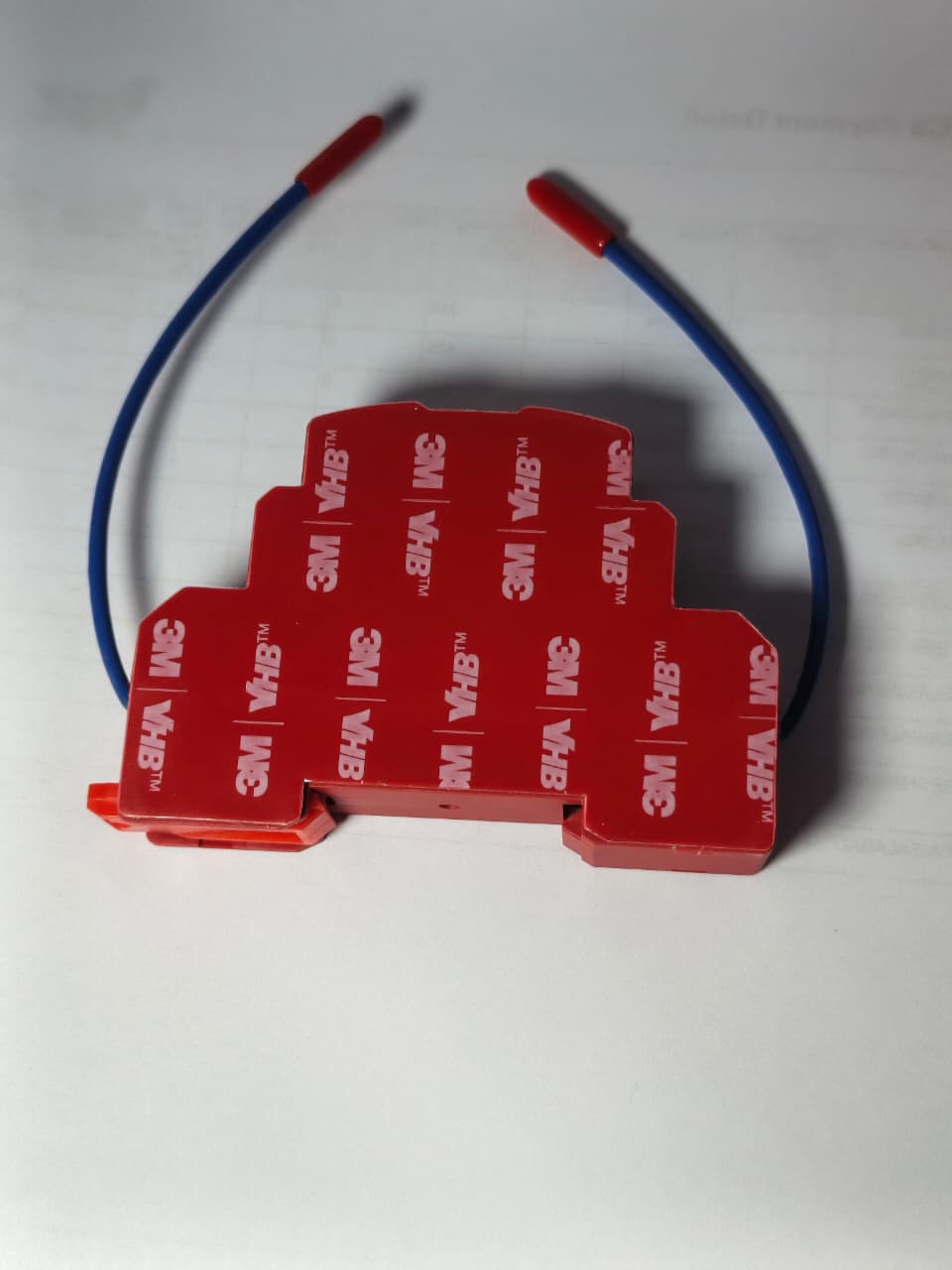 DIGILOG QRR0.01G Heat Aerosol Fire Extinguishing Device - a red, stepped-shape module with 3M VHB adhesive backing and two blue wires with red tips.