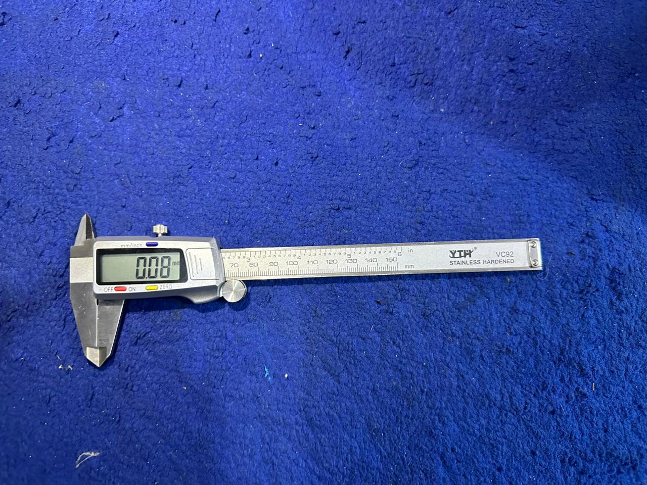 Digital Caliper 150mm - Yth VC92 Stainless Steel Vernier Caliper With LCD Display - shown lying flat on a blue surface with an LCD display reading 0.08 mm.