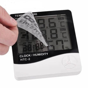 Digital Thermometer And Hygrometer Htc-2 - a hand peeling a protective plastic film off the black and white LCD screen displaying digits.