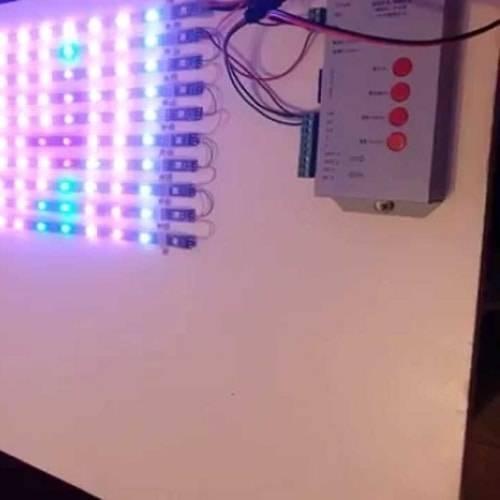 Discontinued Addressable LED Pixel Controller T1000B T-1000B - shown in a grey rectangular housing with four red buttons and wires connected to a strip of illuminated addressable LEDs.