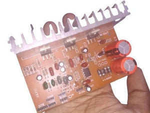 Discontinued Audio Amplifier Board - a brown circuit board with a silver heat sink, two orange capacitors, and labeled speaker, tone, and volume inputs.
