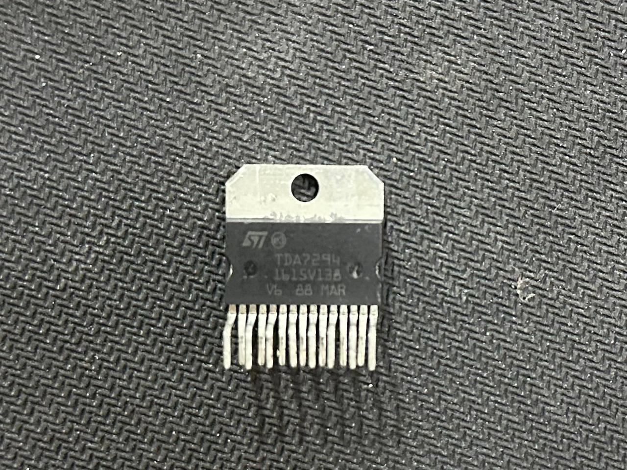 Discontinued TDA7294 100W Audio Power Amplifier IC - TO-220-15 Package - a black rectangular electronic component with fifteen metal pins and a top mounting hole, shown close-up.