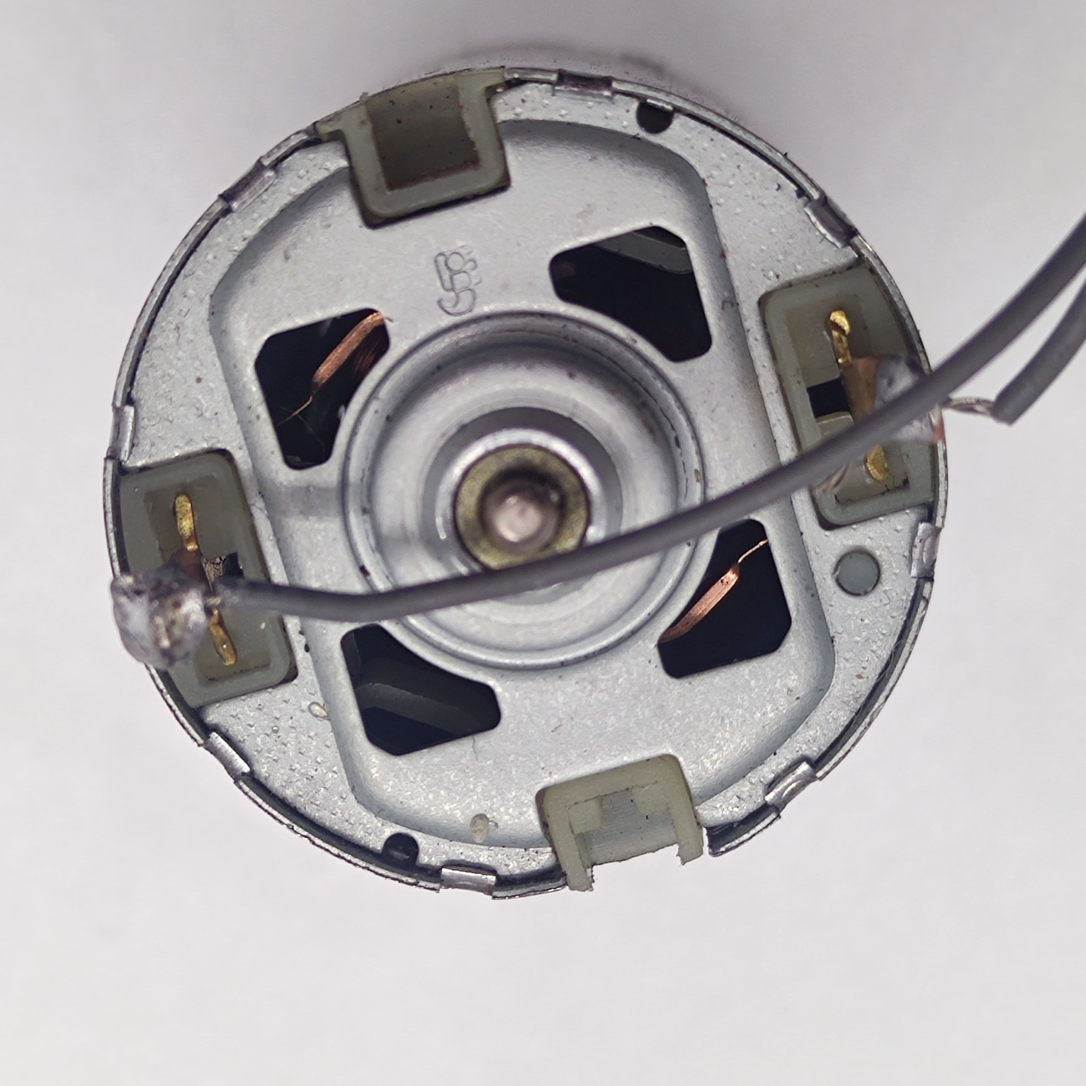DIY DC Motor DC 3V To 25V Torque Mini Motor 17500RPM - a close-up view of the silver circular back end showing two metal terminals with a wire attached.