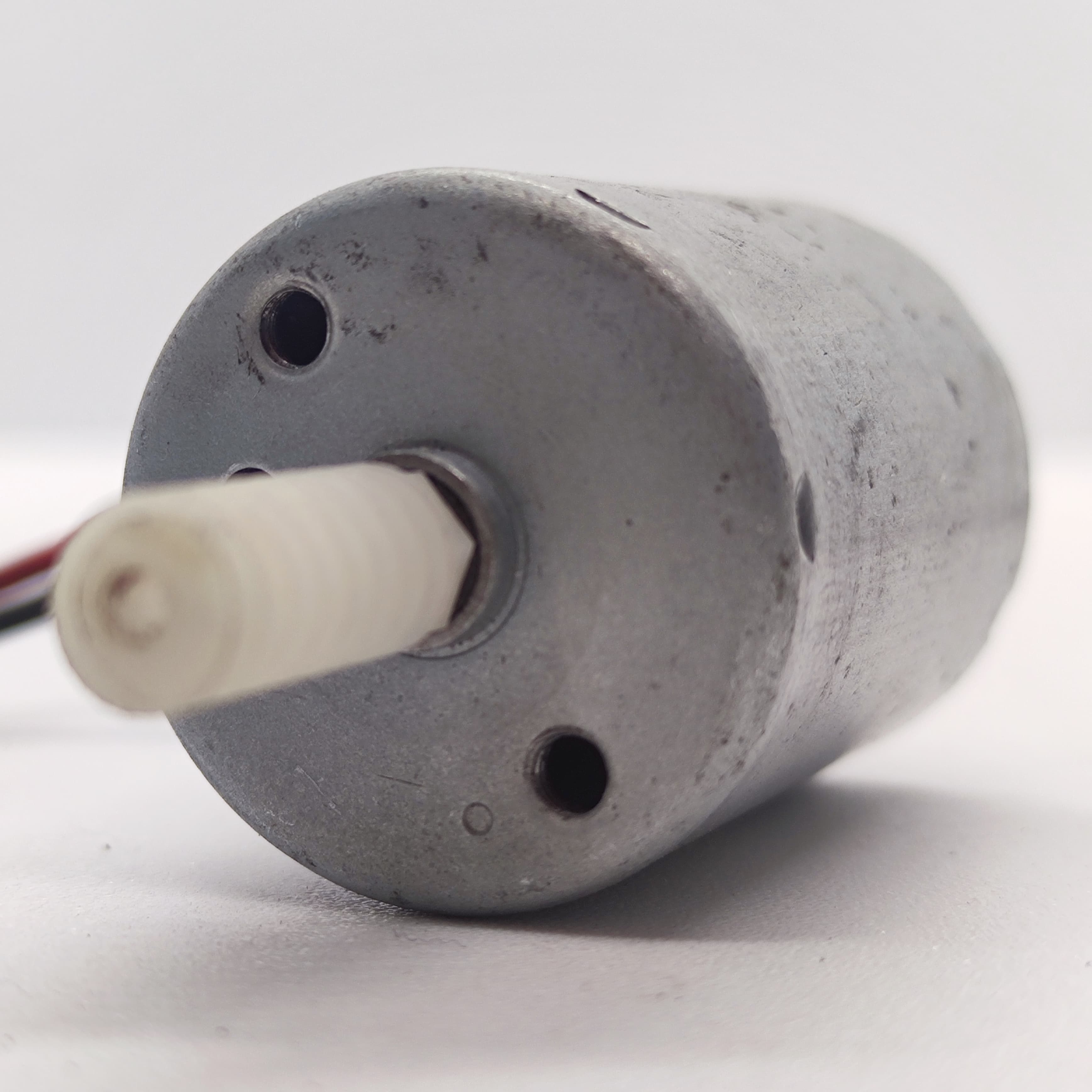 DIY Mini 5vdc DC Motor - shown as a close-up of a silver cylindrical motor body with a white plastic gear attached to the front shaft and two wires.