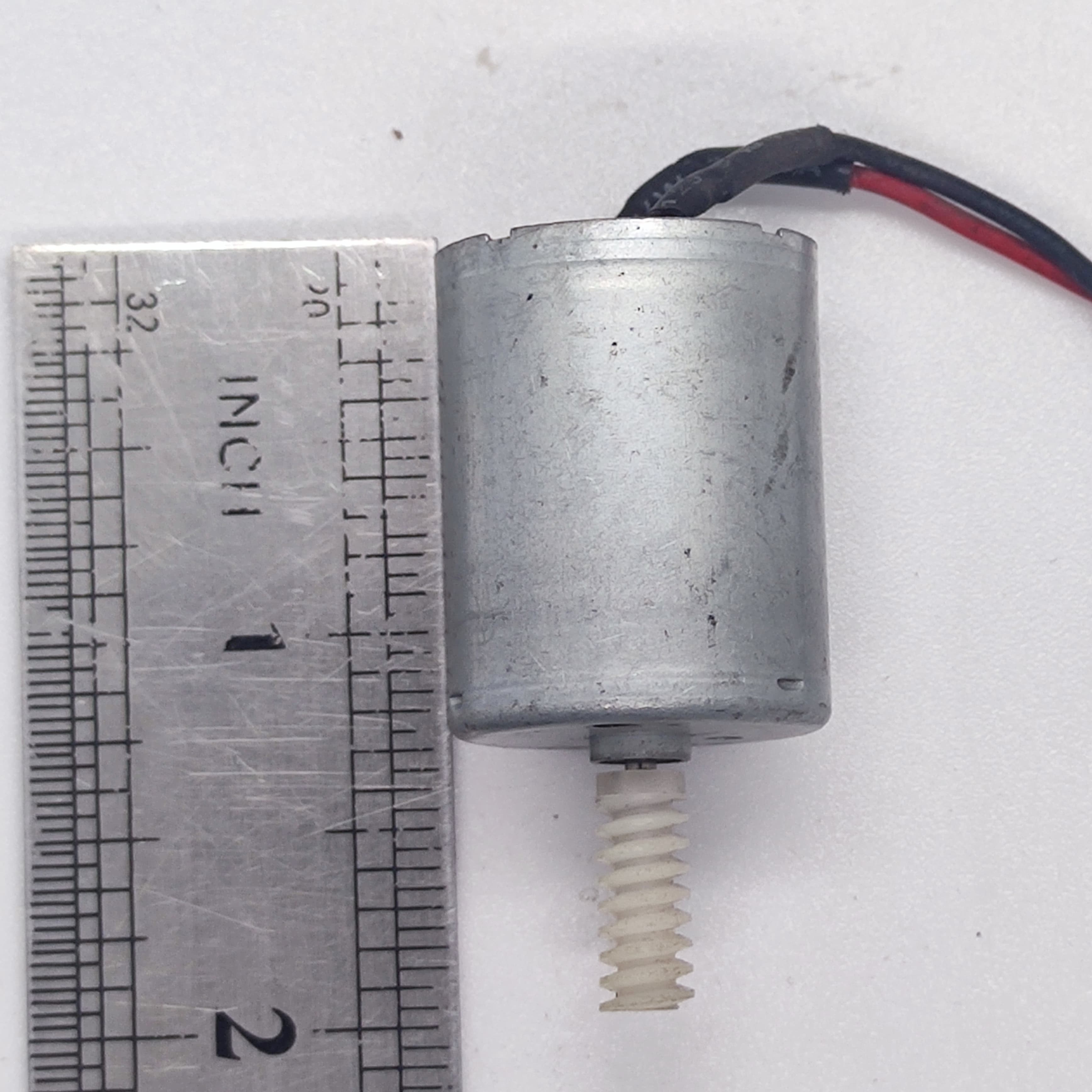 DIY Mini 5vdc DC Motor - shown next to a metal ruler for scale, featuring a cylindrical silver motor body with a white plastic worm gear on the shaft.