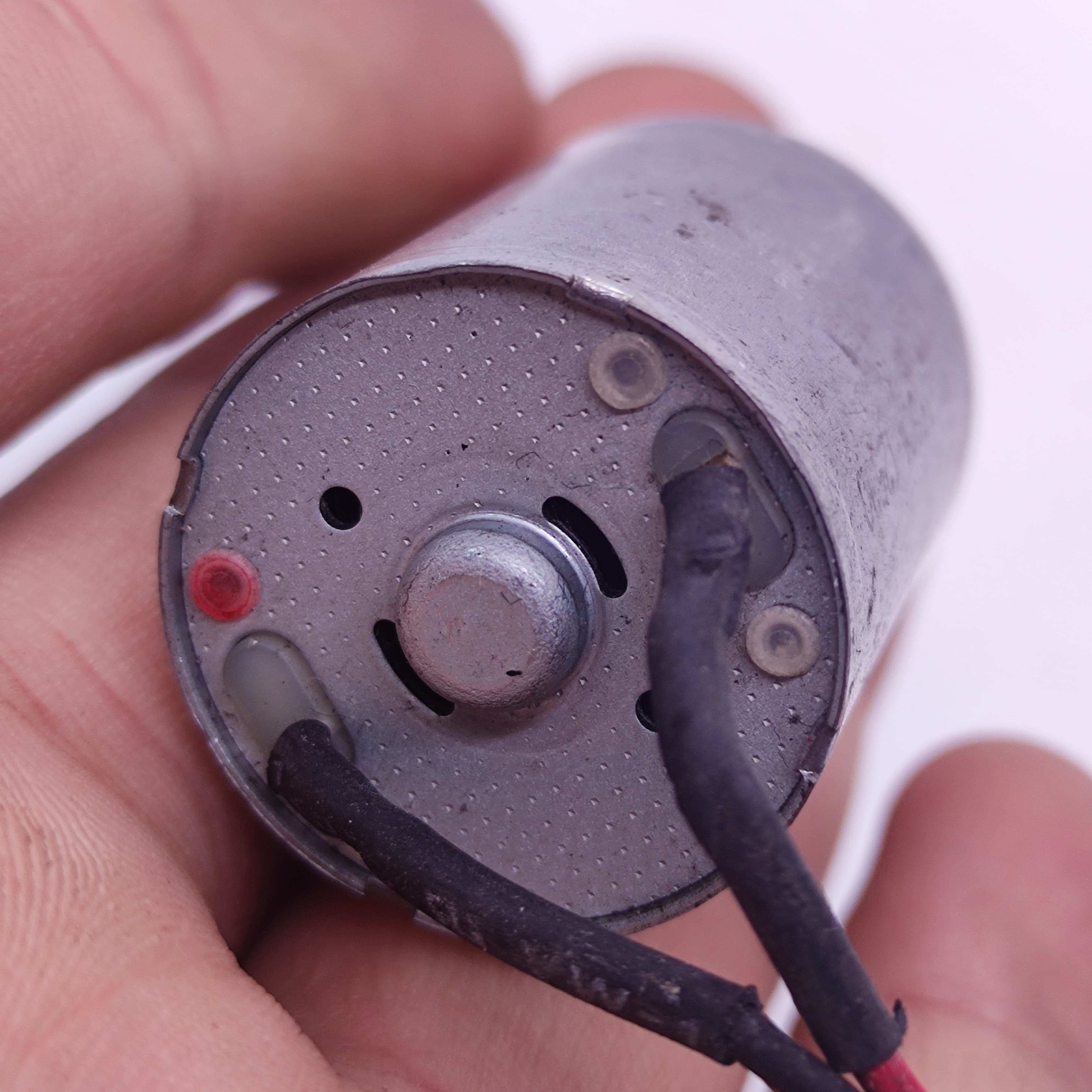 DIY Mini 5vdc DC Motor - a close-up view of the rear end showing the silver cylindrical casing, two soldered wire terminals, and a central shaft.