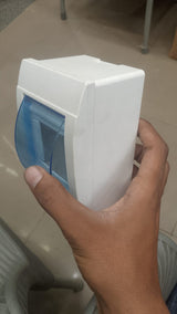 Double Pole Breaker Fitting Box - a white plastic enclosure held in a hand featuring a hinged, translucent blue protective cover.