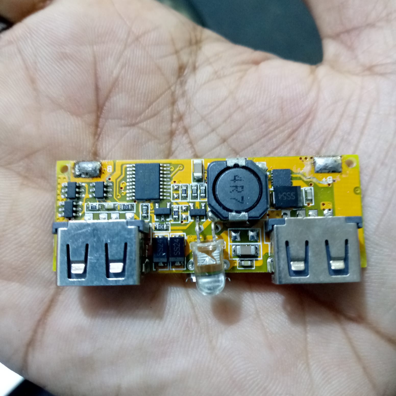 Dual USB 18650 Battery Charger Power Bank Module 5V 1A 2A - a yellow circuit board featuring two USB ports, a central LED, and an inductor coil.
