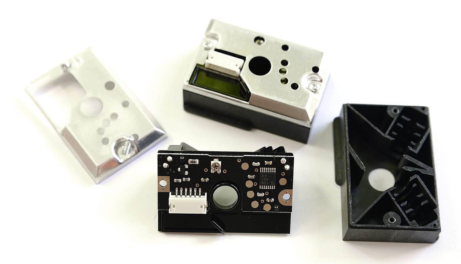 Dust Sensor Module GP2Y1010AU0F Compact Optical Dust Sensor - shown disassembled into its metal casing, black plastic housing, and internal circuit board with a white connector port.