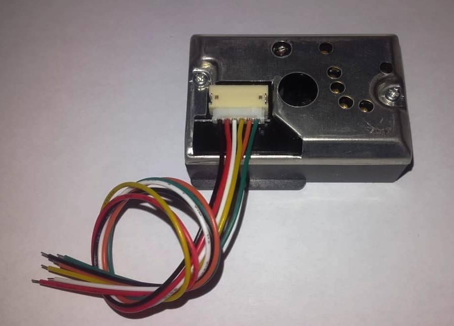 Dust Sensor Module GP2Y1010AU0F Compact Optical Dust Sensor - a rectangular metal and black plastic sensor with a white six-pin connector and a multi-coloured wiring harness attached.