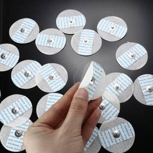 Ecg Electrodes With Metal Snap And Low Impedance Solid Medical Conductive Gel - a hand peeling the protective film off a circular white adhesive electrode.