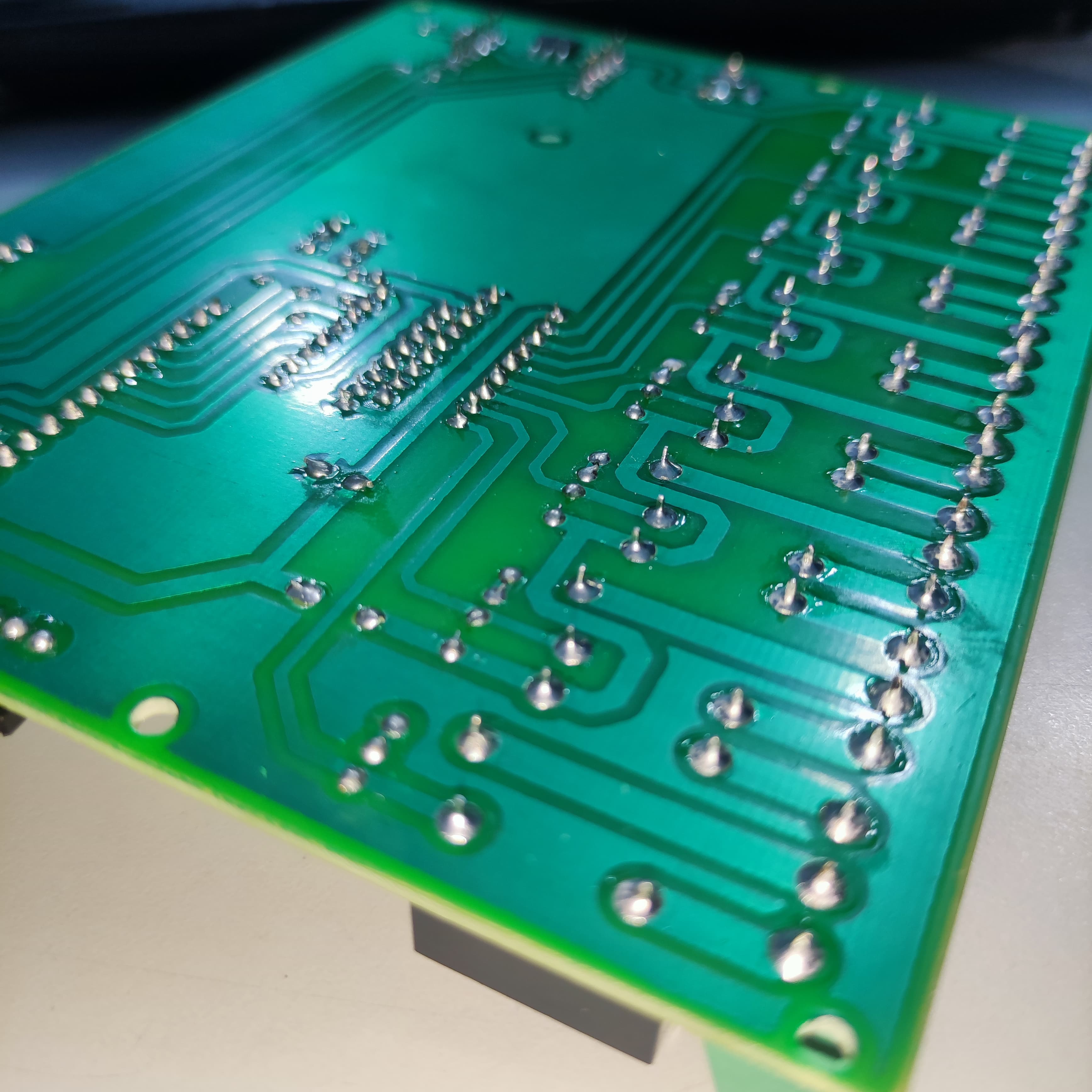 ESP32 Based 8 Channel Relay Board Micro Controller Board WiFi LAN Bluetooth - a close-up view of the green printed circuit board underside showing soldered through-hole component pins and traces.