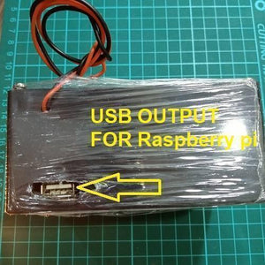 Euler | Raspberry Pi UPS 5V Battery Backup - a black rectangular device wrapped in plastic, featuring a USB output port and two attached power wires.