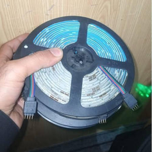 Faulty RGB LED Strip Lot 5 Meter 5 Meter 30 LED Per Meter Dusty Lot - a coiled strip of LED lights with a four-pin connector held in a hand.
