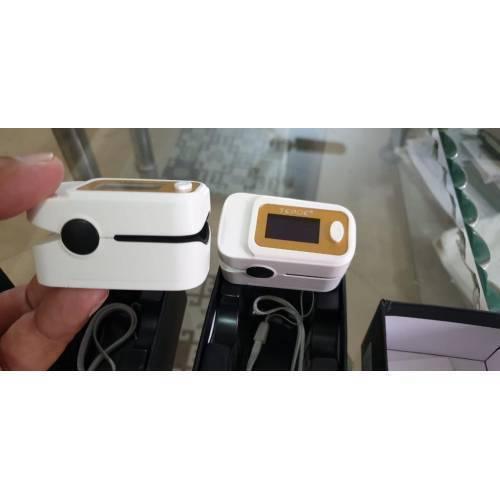 Finger Pulse Digital Oximeter-SPO2 - two white and gold devices with display screens, buttons, and lanyards inside their open packaging boxes.