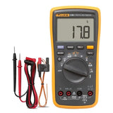 Fluke 17B+ Digital Multimeter - a yellow handheld device with a display reading 17.8, a rotary dial, buttons, ports, and two test lead sets.