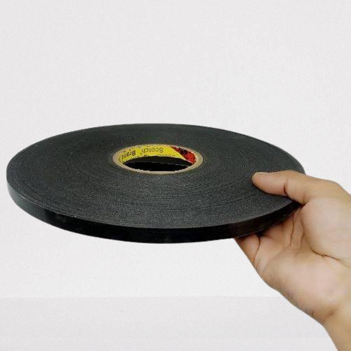 Foam Tape Double Sided For LED Extrusion Profiles - a roll of black adhesive foam tape held in a hand against a plain background.