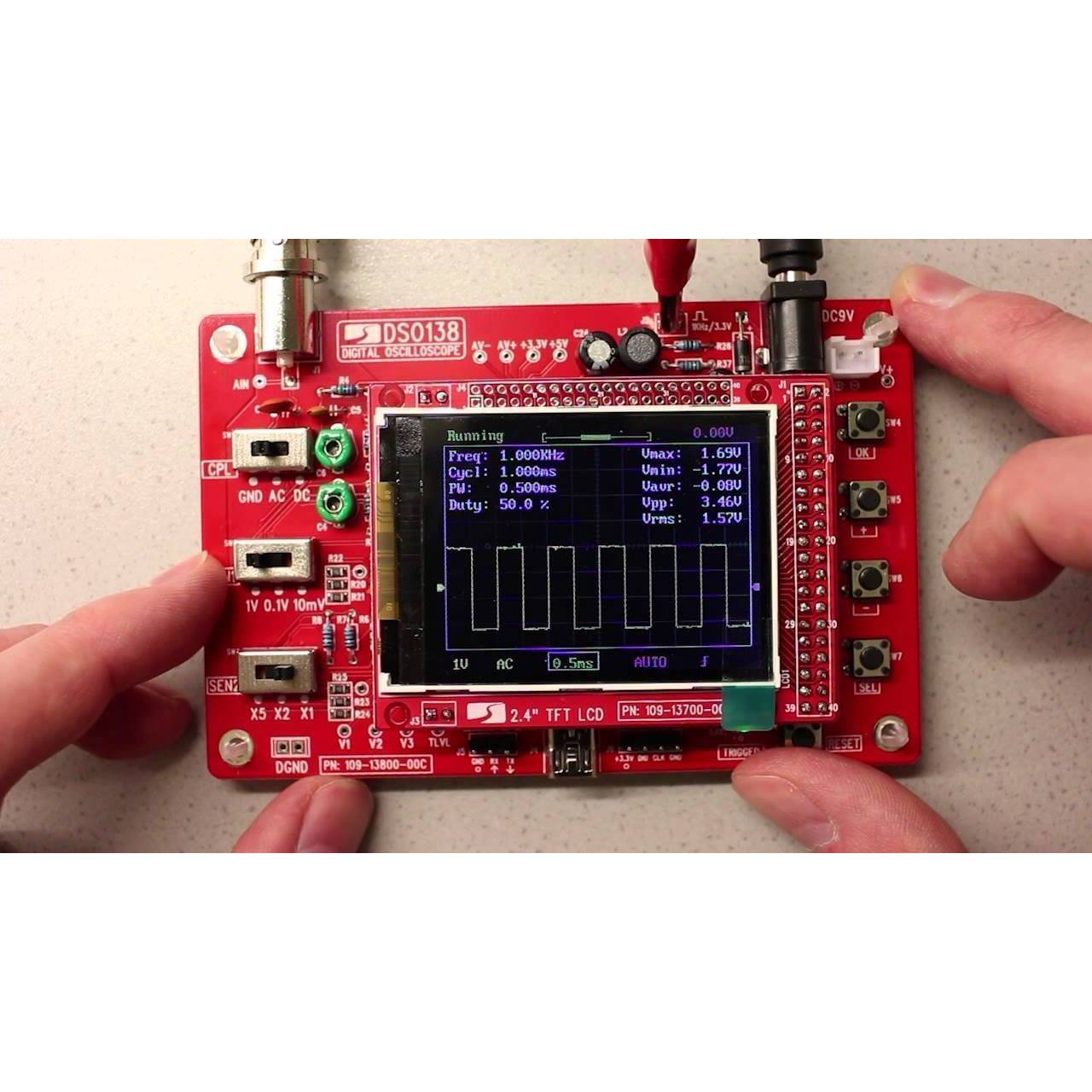 Fully Assembled DSO138 2.4″ TFT Digital Oscilloscope - a red circuit board with a screen displaying a square wave signal and settings.