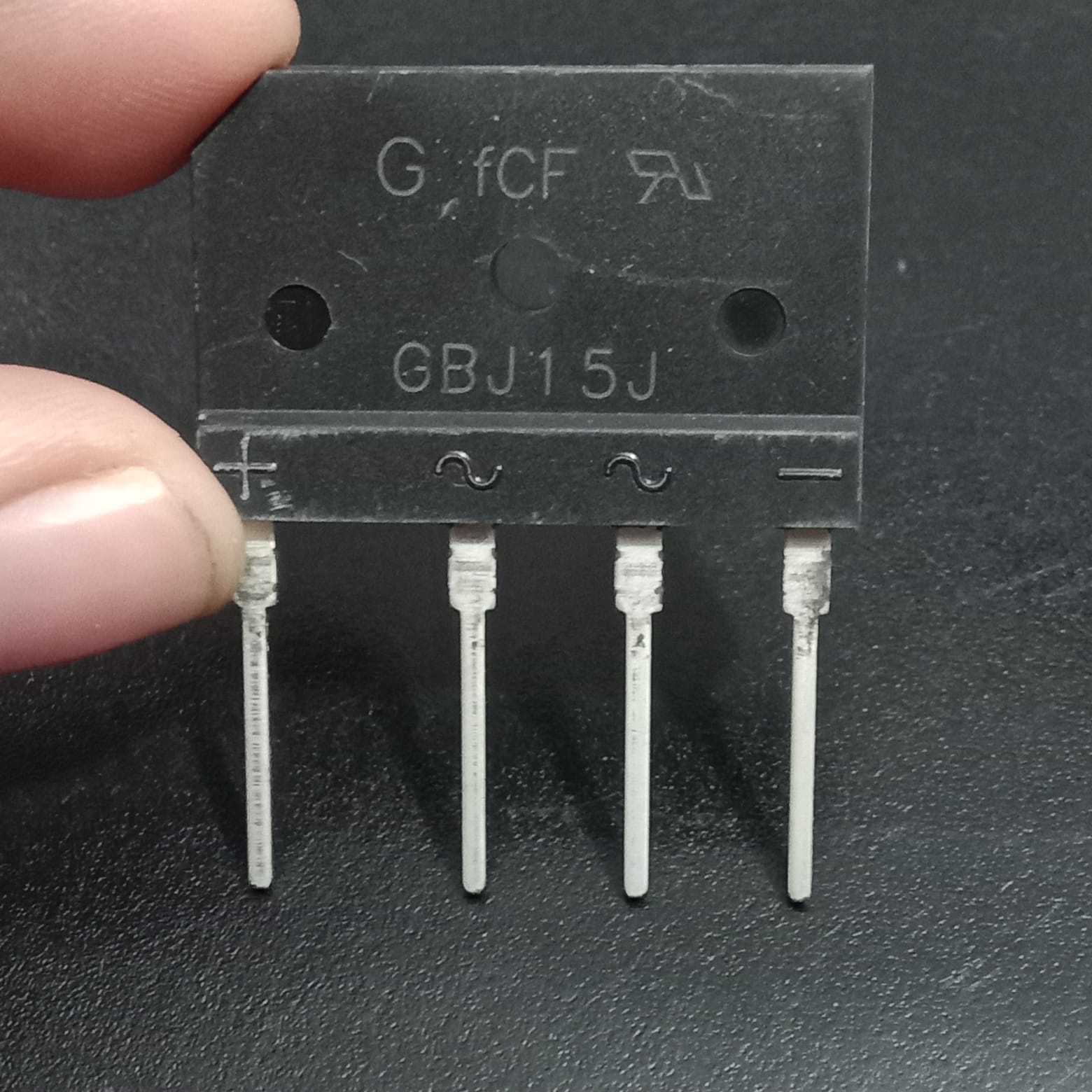 GBJ15J 600V 15A Single-Phase Bridge Rectifier - a black rectangular electronic component with four pins and labels for positive, negative, and AC inputs.