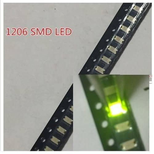 Green SMD 1206 LED Super Bright Light Emitting Diode - shown in a close-up view of multiple units on a black carrier tape, with one LED illuminated green.