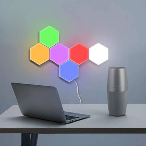 Green Touch Light Wall Mount Magnetic Modular (1pc) - shown as a cluster of six illuminated hexagonal wall lights in various colors above a laptop and speaker.