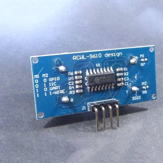 HC-SR04 Hc SR04 Arduino Ultrasonic Sensor - RCWL-9610 ultrasonic sensor module, showing a blue rectangular circuit board with a central chip, surface-mount components, and a four-pin header.