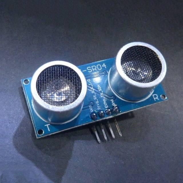 HC-SR04 Hc SR04 Arduino Ultrasonic Sensor - two silver circular transducers mounted on a blue rectangular circuit board with four output pins.