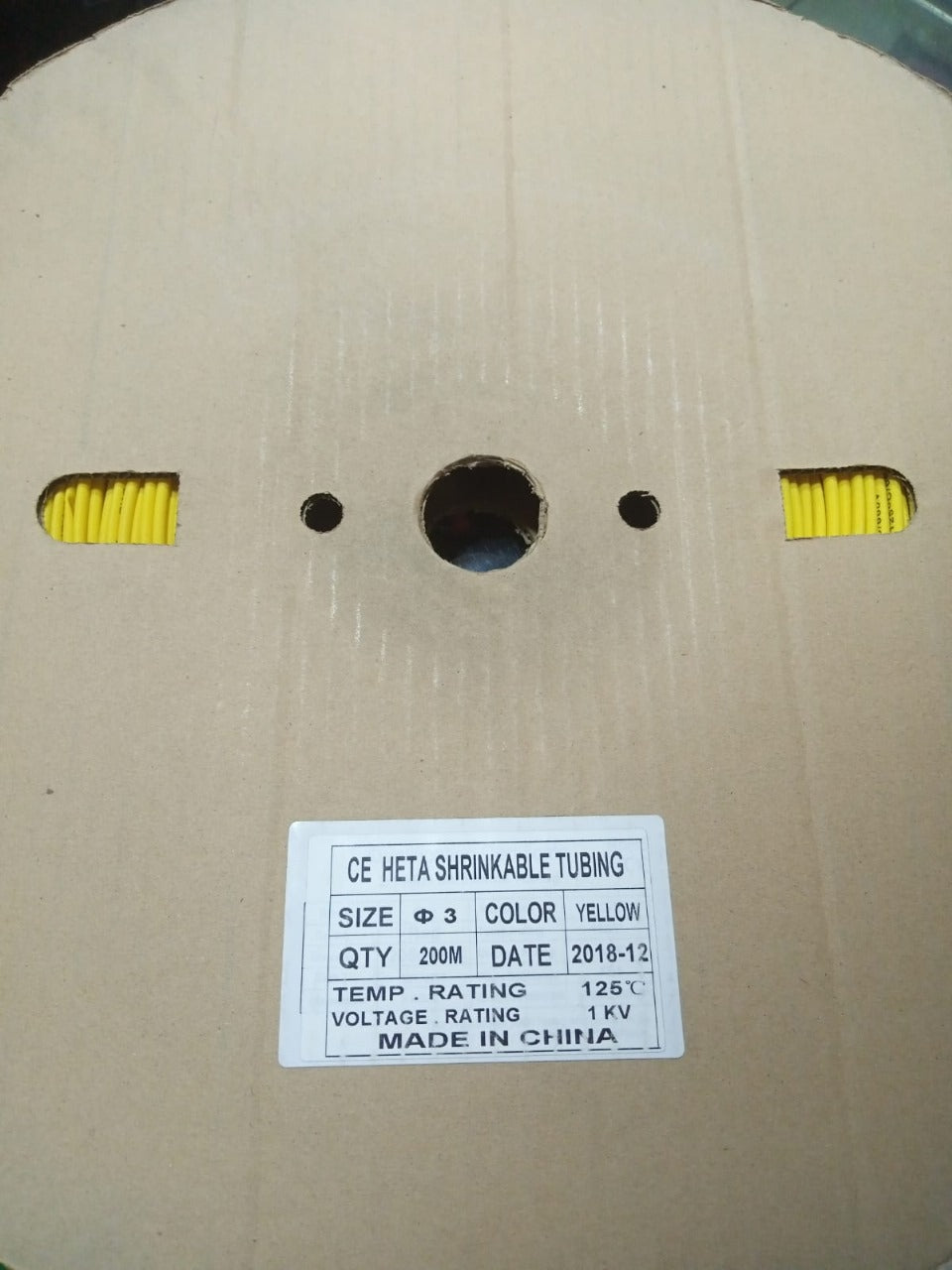 Heat Shrink Sleeve Yellow Color 200Meter Roll - shown as a yellow coiled tube inside a cardboard spool with a product specification label attached.