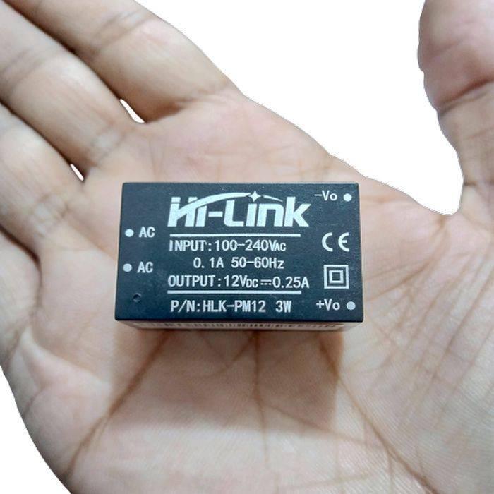 Hi Link Hlk PM12 12V/3W Switch Power Supply Module - a small black rectangular component held in a palm, showing input and output pin labels printed on its face.
