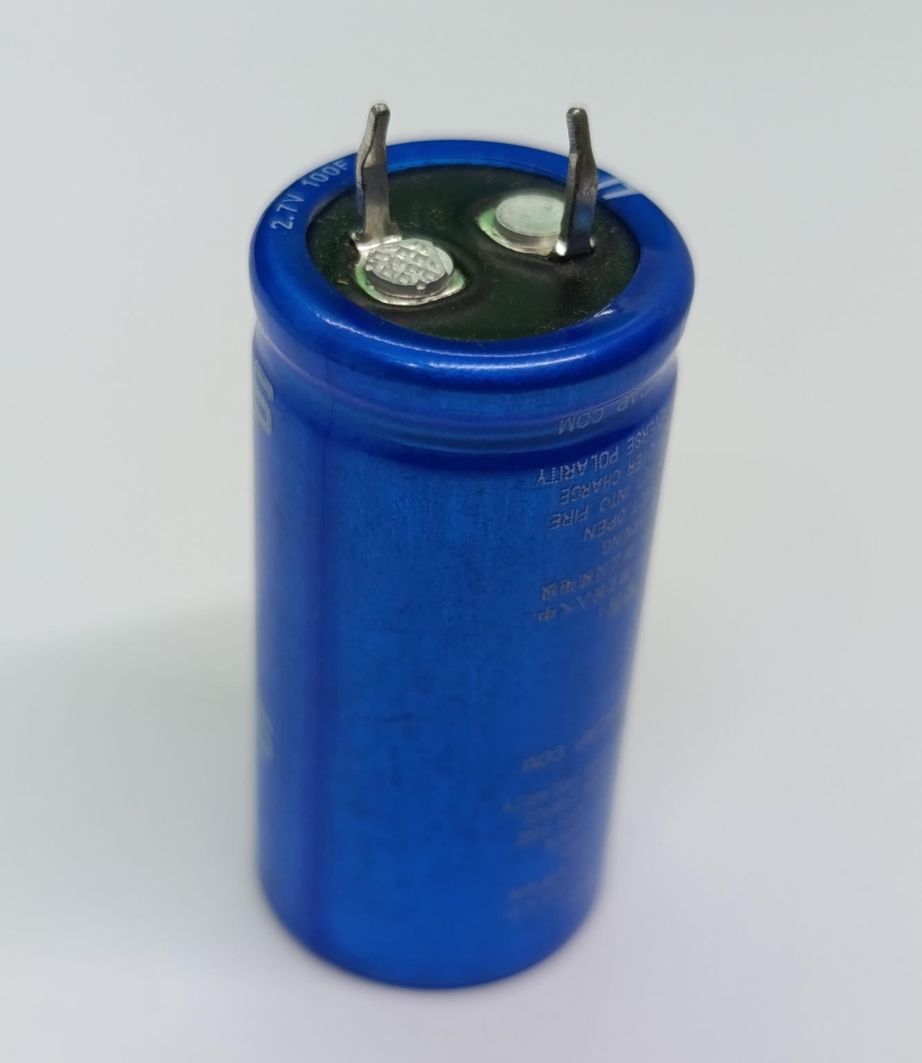 High Quality 2.7V 100F Super Capacitor - a cylindrical blue electronic component with two metal terminals on top, viewed from a high angle.