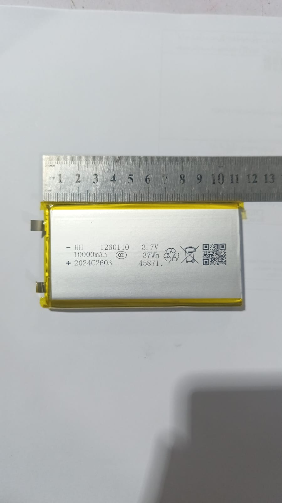 High Quality 3.7V 10000mAh 1260110 Polymer Lithium Ion Li-ion Rechargeable Battery For Toy Power Bank GPS Table E-book Batteries - shown with a metal ruler measuring its length, displaying technical specifications and a QR code on its silver surface.