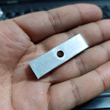 IGBT Fitting - a close-up of a small, rectangular, silver-coloured metal mounting plate with a single circular hole in the center held in a hand.
