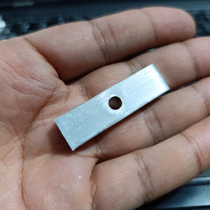 IGBT Fitting - a close-up of a small, rectangular, silver-coloured metal mounting plate with a single circular hole in the center held in a hand.