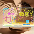 Transparent LED writing and message board with colourful drawings on a tabletop base