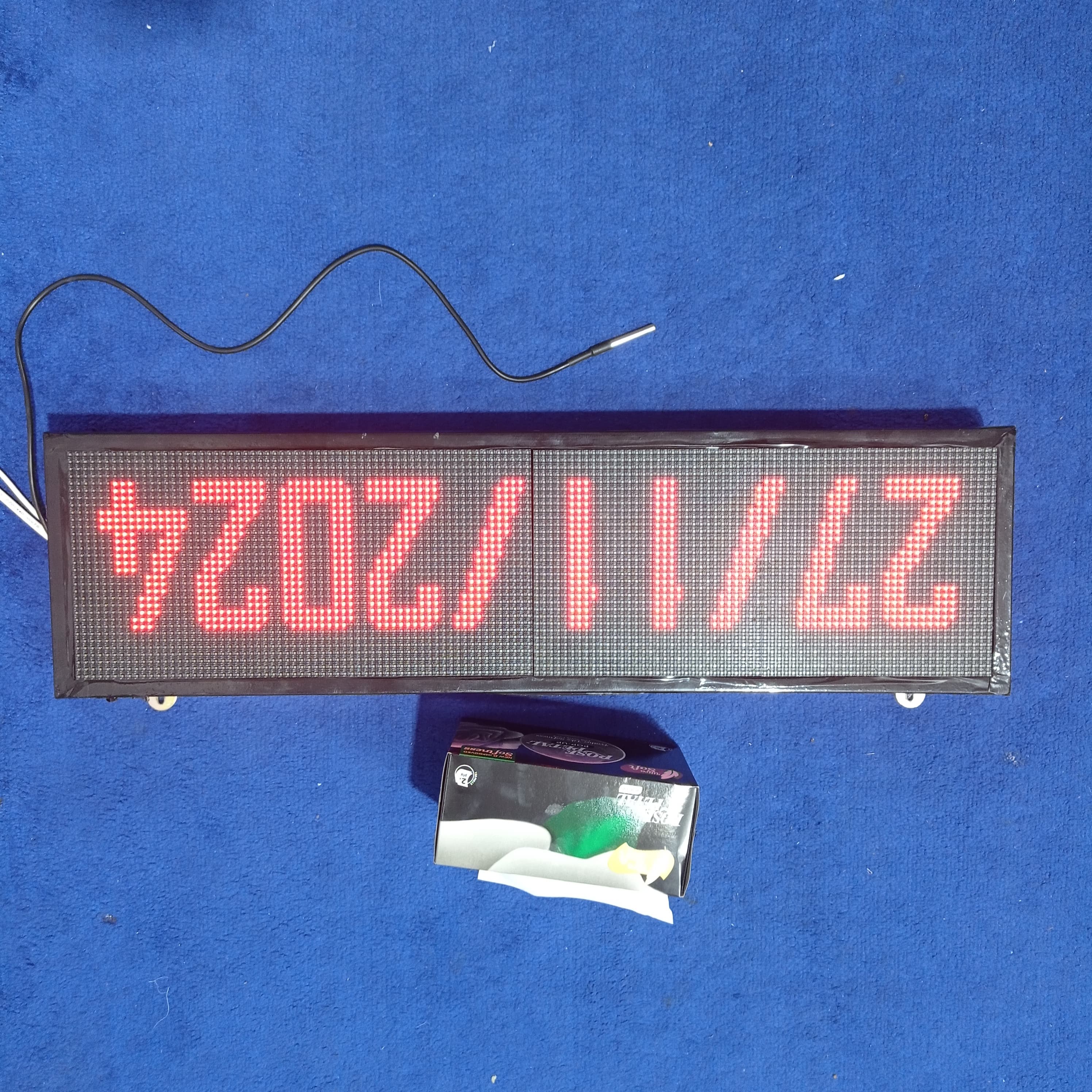 Industrial Clock With Temperature Display RGB Display - the date 27/11/2024 on its screen, with a temperature sensor probe and a tissue box nearby.