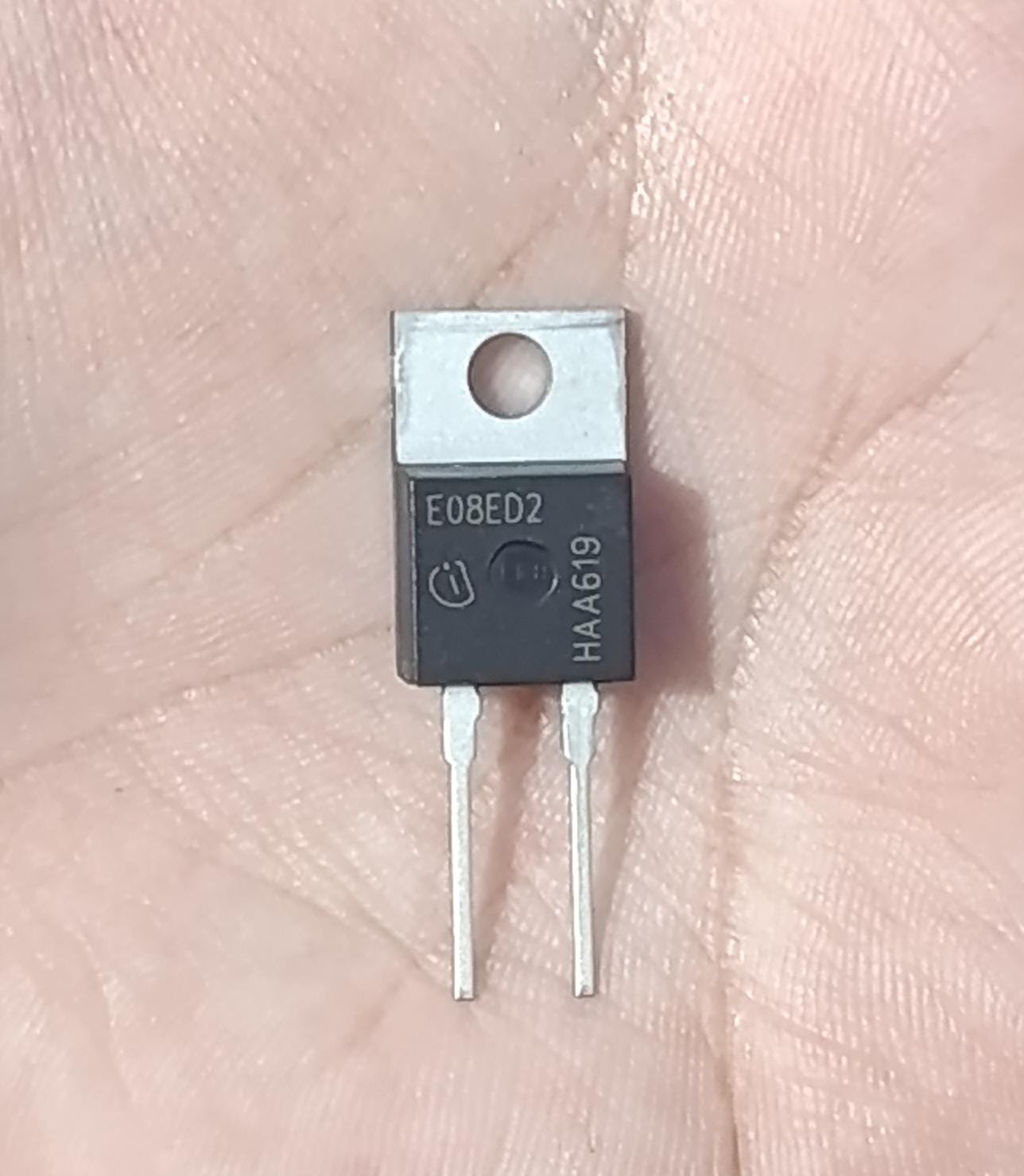Infineon E08ED2 650V 8A Rapid Switching Diode (TO-220-2) - a black TO-220-2 electronic component with two metal pins, held against a person's palm.