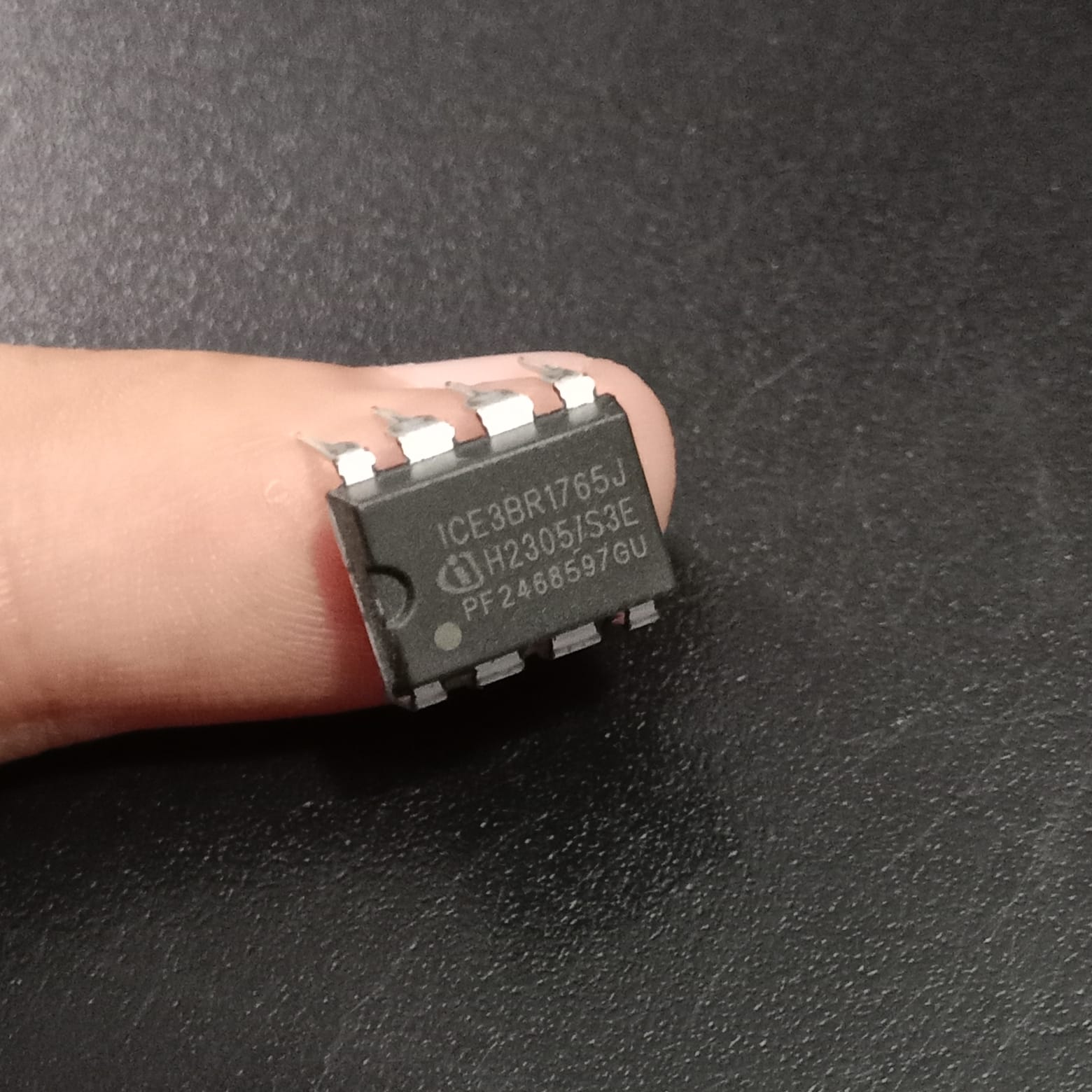 Infineon ICE3BR1765J Off-Line SMPS Controller IC - a black 8-pin integrated circuit held by a finger, showing its printed model number and markings.