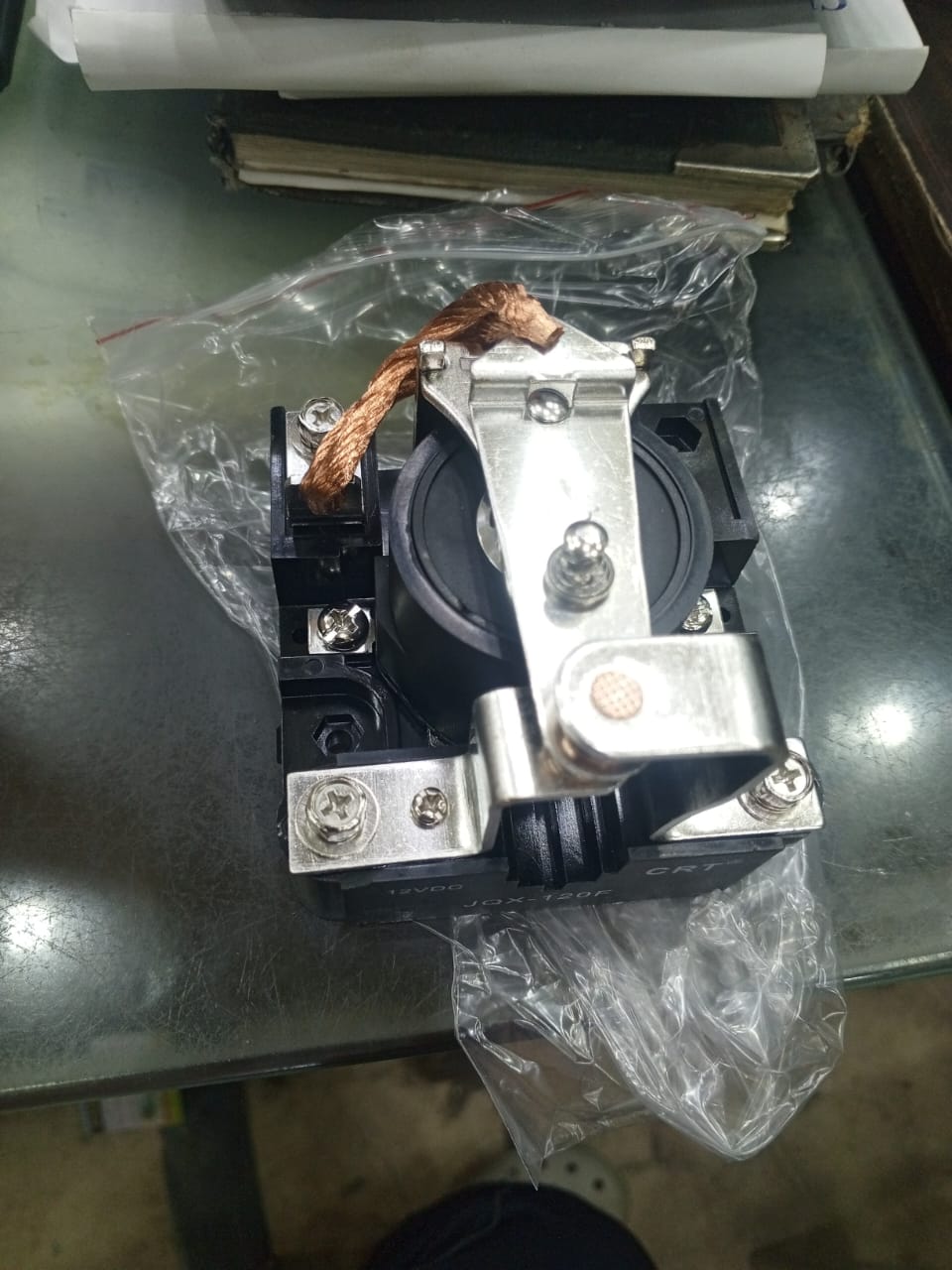 Jqx 120F 12V Relay - a black electromagnetic relay with a copper braided wire and metal contact arm, shown inside a clear plastic bag.