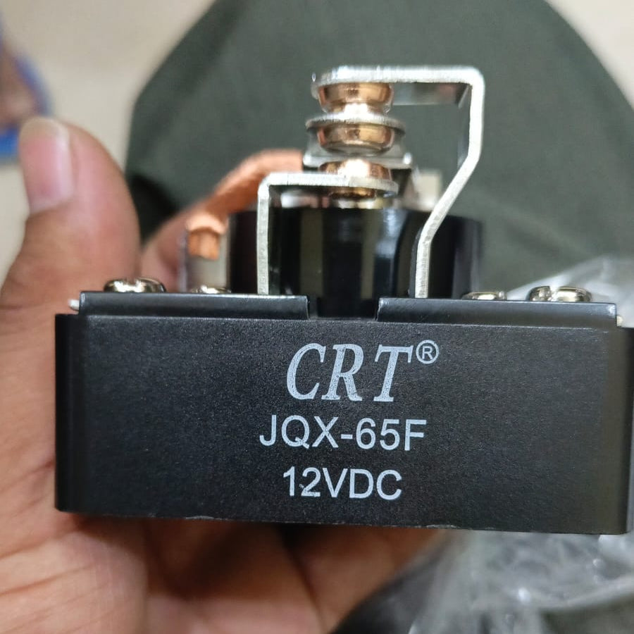 Jqx 65F 12V Relay - a black electronic component with exposed copper-colored metal terminals, held in a hand with the model number printed on the side.