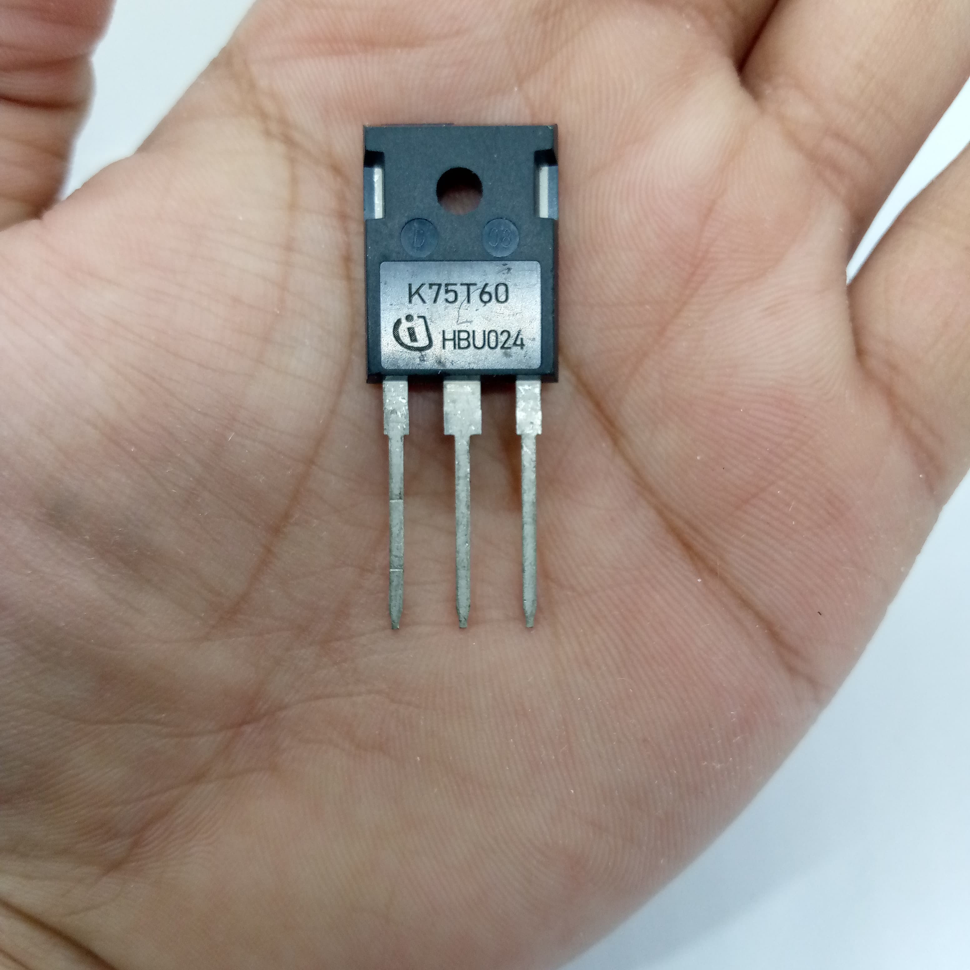 K75T60 IGBT IKW75N60T 600V 75A IGBT - shown as a close-up of a black, three-pin electronic component held in a person's palm.