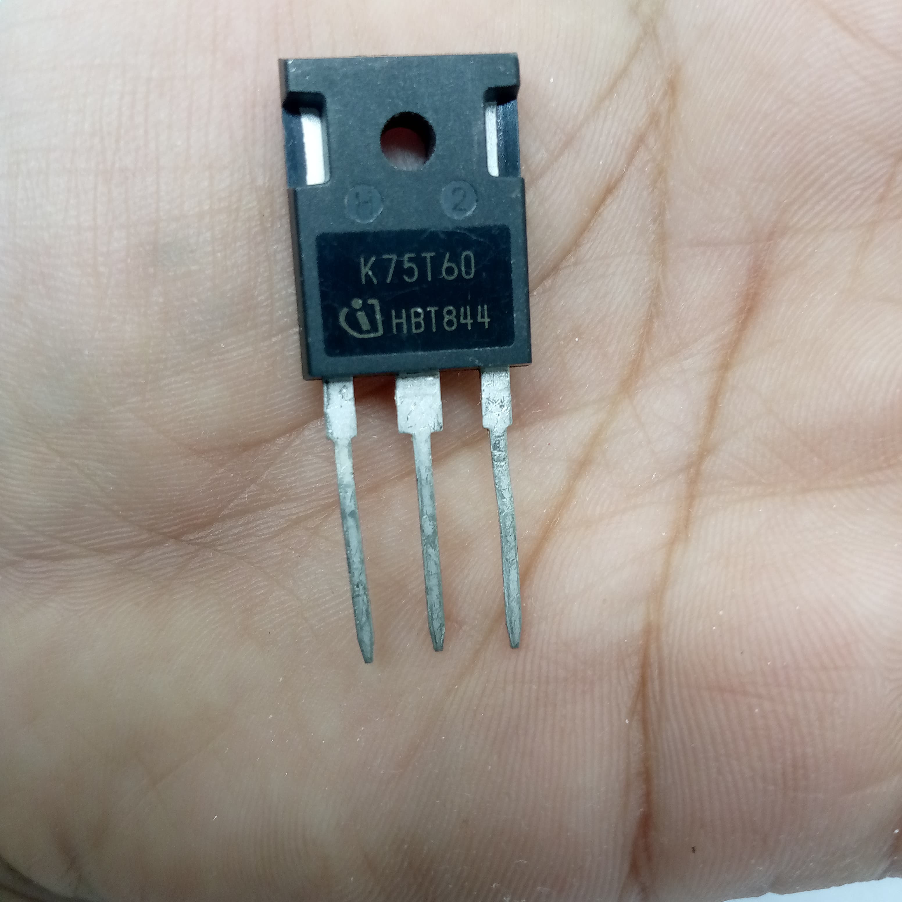 K75T60 IGBT IKW75N60T 600V 75A IGBT - a black three-pin electronic transistor held in a hand, with the text "K75T60" and "HBT844" printed on its front surface.