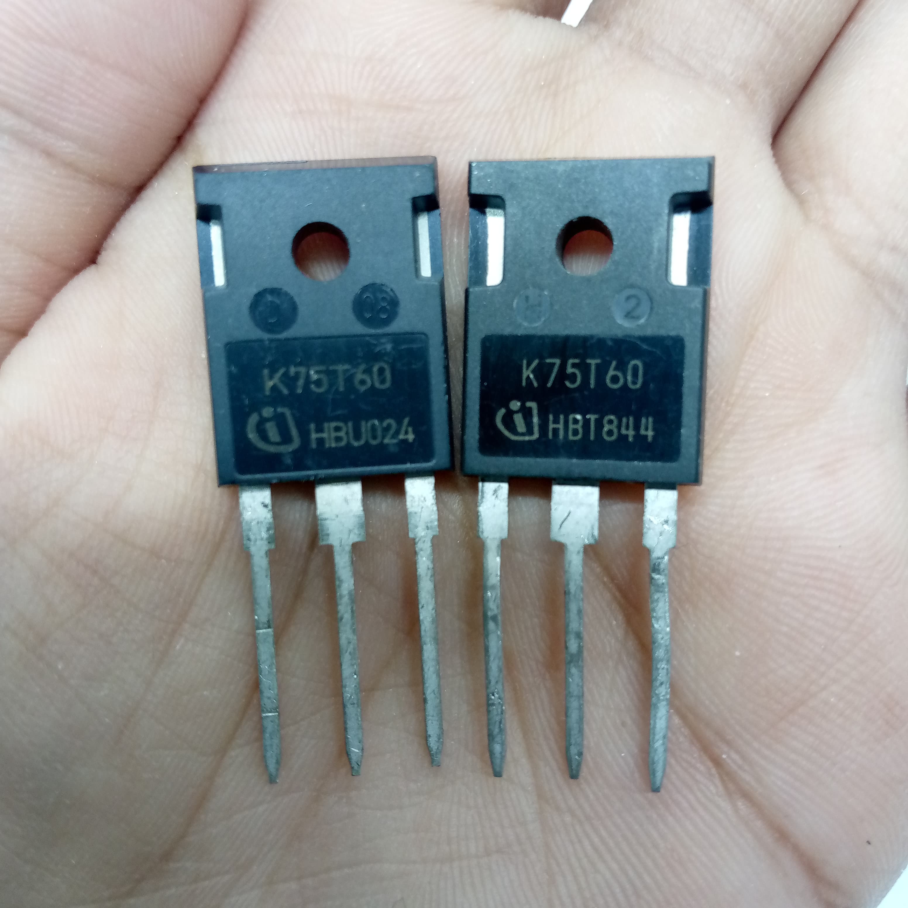 K75T60 IGBT IKW75N60T 600V 75A IGBT - shown as two identical black three-pin semiconductor components held in a hand, displaying model markings.