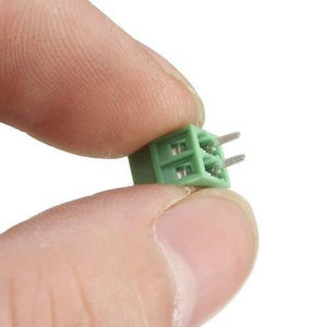 Kf 128 2p 5mm Pitch 2 Pin PCB Screw Terminal Block Connector - Digilog Pakistan - shown in a close-up view held between two fingers.