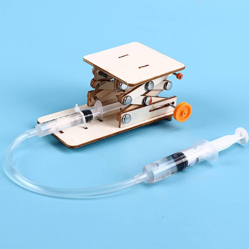 Kids DIY Hydraulic Lift Table Model Scientific Experiment Kit Educational STEM Toy - a wooden scissor-lift mechanism connected by plastic tubing to a handheld syringe.